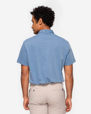 Heathered light blue golf performance polo with navy blue collar detail and two white button placket paired with kahki shorts 
